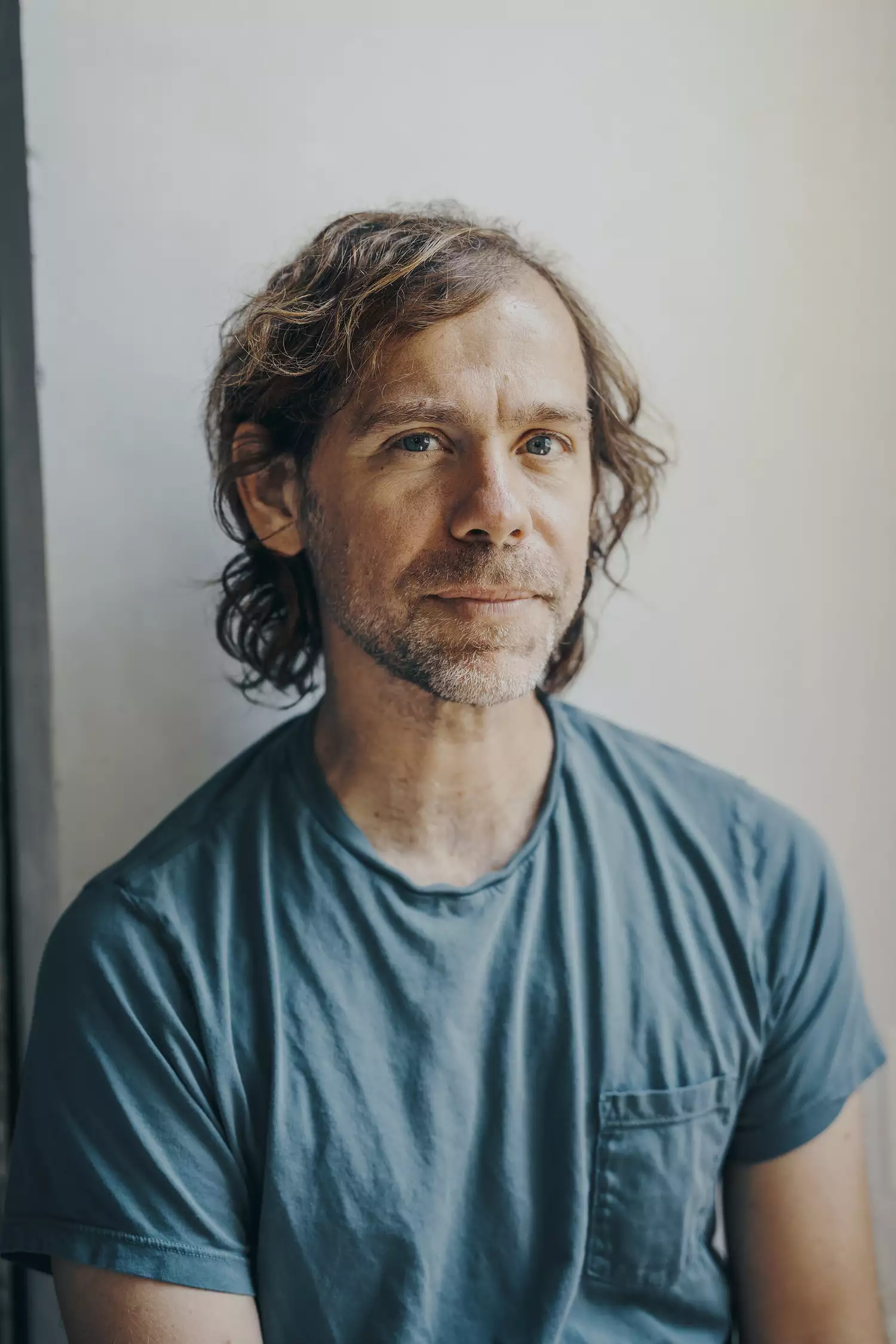 Headshot of Aaron Dessner smiling and wearing a blue t-shirt