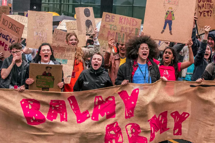 Photograph from a march through Manchester City Centre as part of MIF23. It shows people holding a large banner that reads 'Balmy Army'.