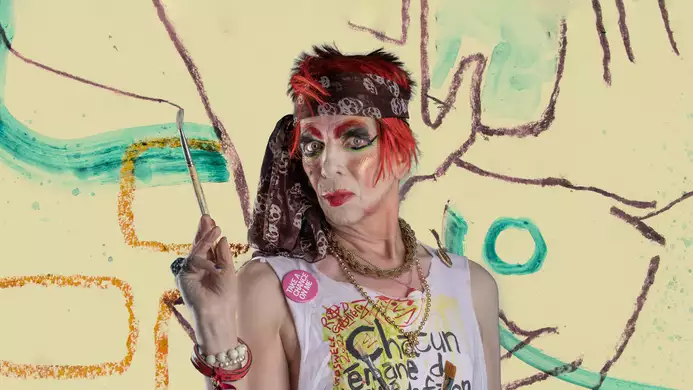 David Hoyle in a sleevless t-shirt holding paintbrushes