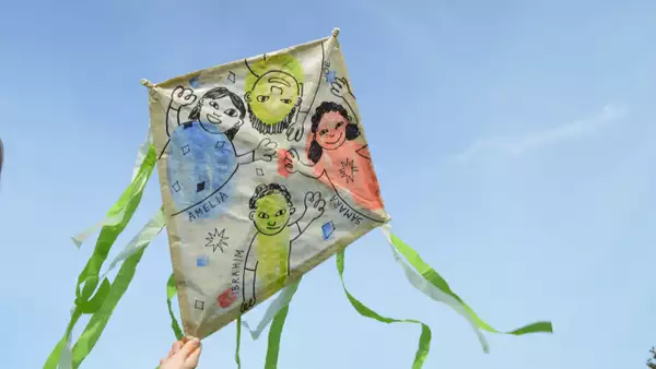 A hand drawn kite with green paper ribbons in the sky
