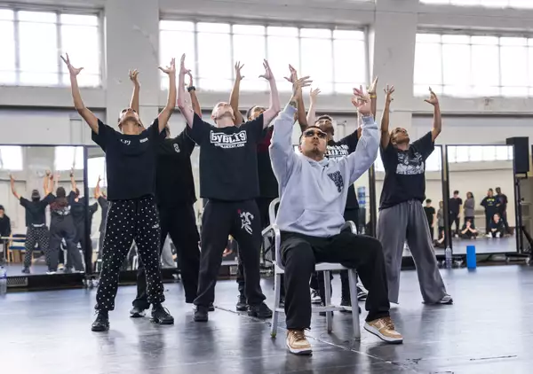 Dancers for Free Your Mind with arms raised, one seated, in rehearsals