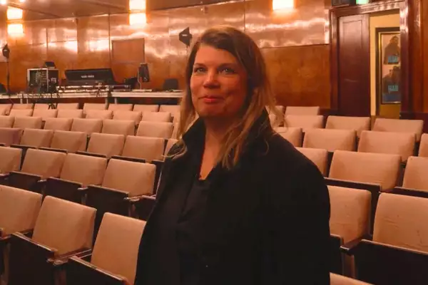 Helgard Haug of Rimini Protokoll stands in front of a map of the world