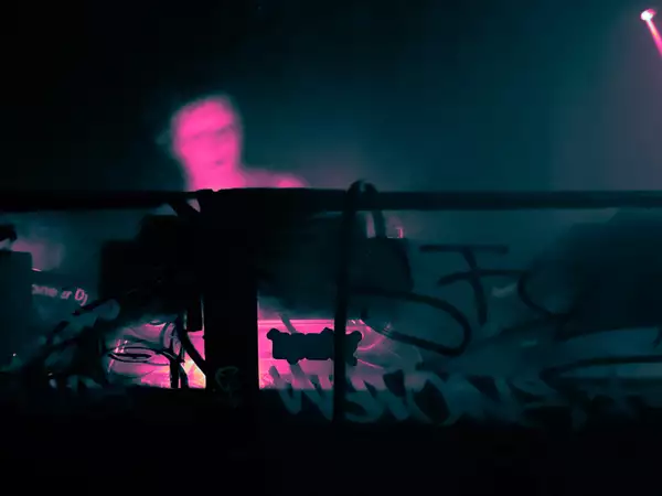 A person DJs in a booth decorated with graffiti and stickers