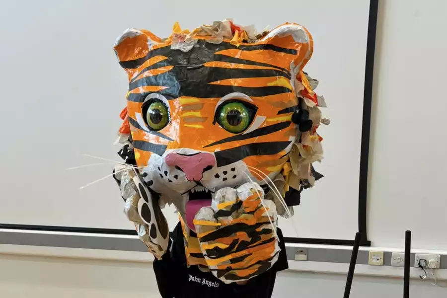 A child wearing a giant tiger puppet on their head
