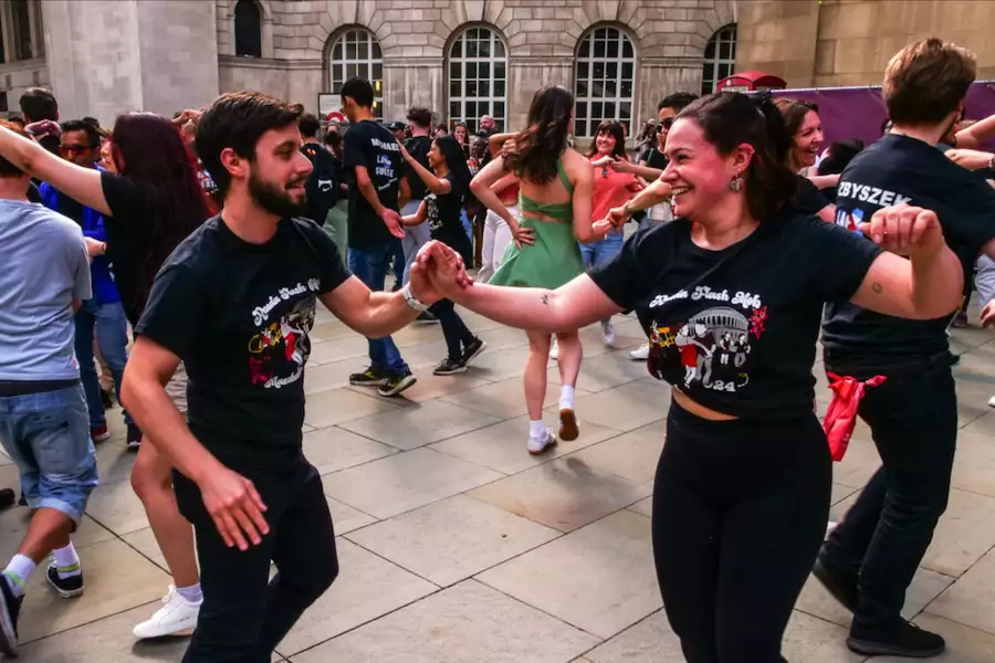 Two people dancing and smiling. They are in a crowd of people dancing outside.
