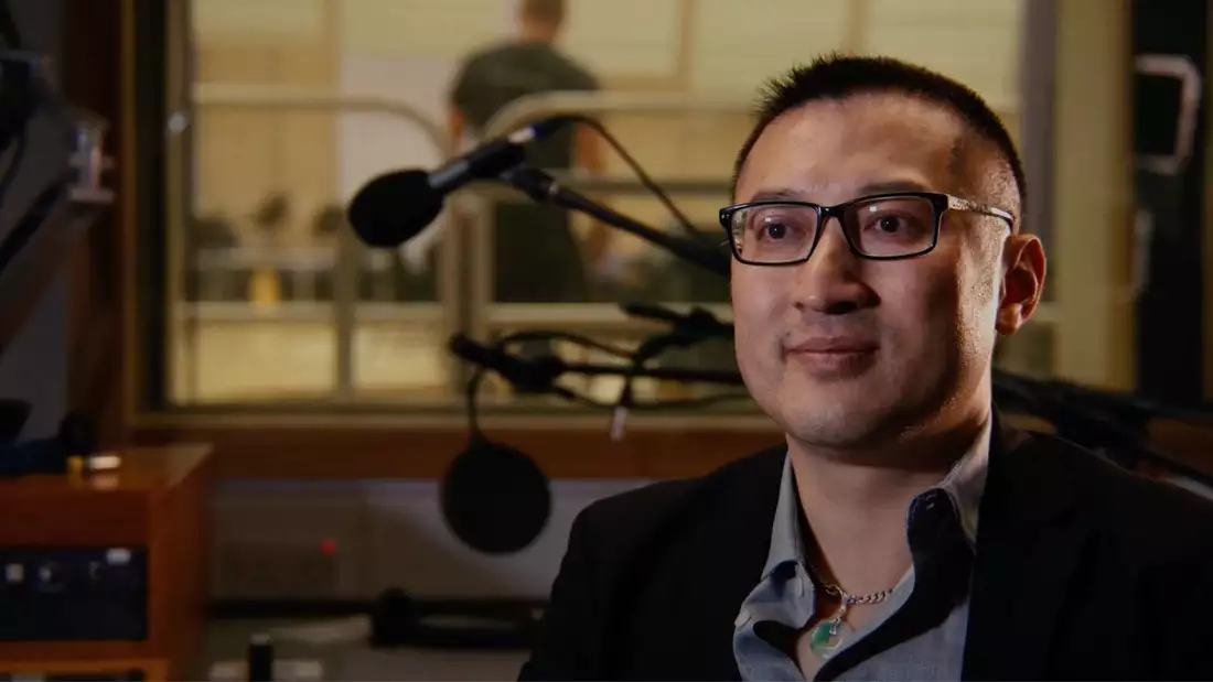 Huang Ruo smiling inside a recording studio with microphones behind him